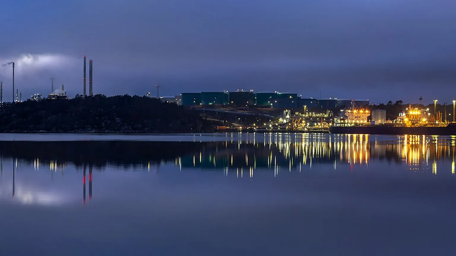 AI illustration: Oil refinery at blue hour with fog over the water
