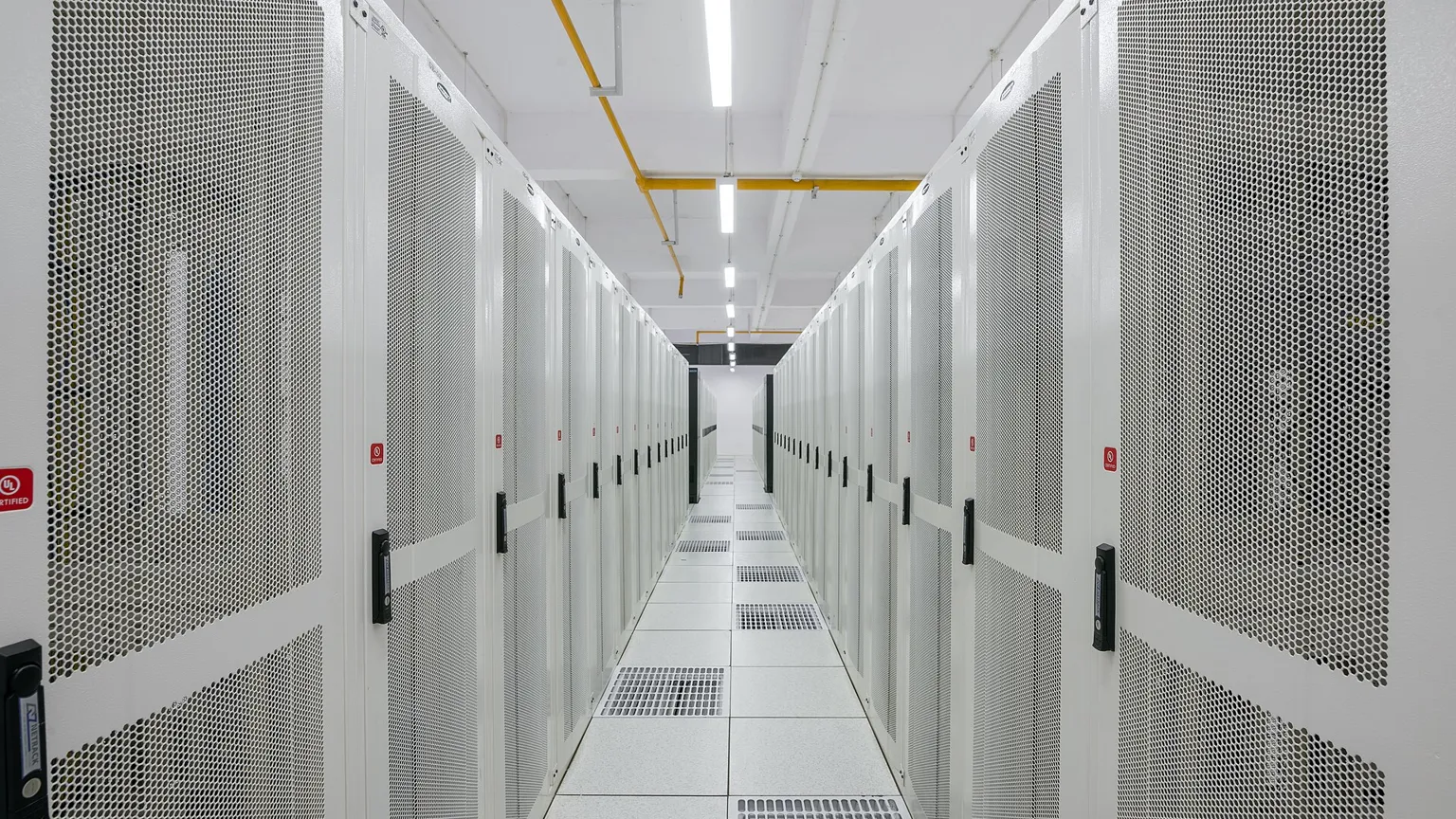 A corridor between rows of server racks in a data centre