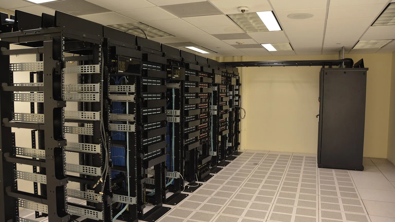 A security engineer reviewing server logs on several monitors at night