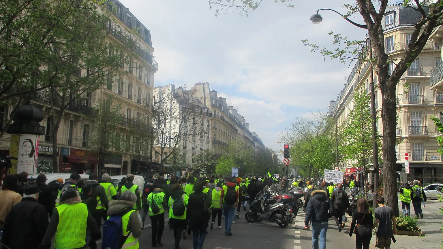 A large street march on a Paris boulevard with blank placards and French flags