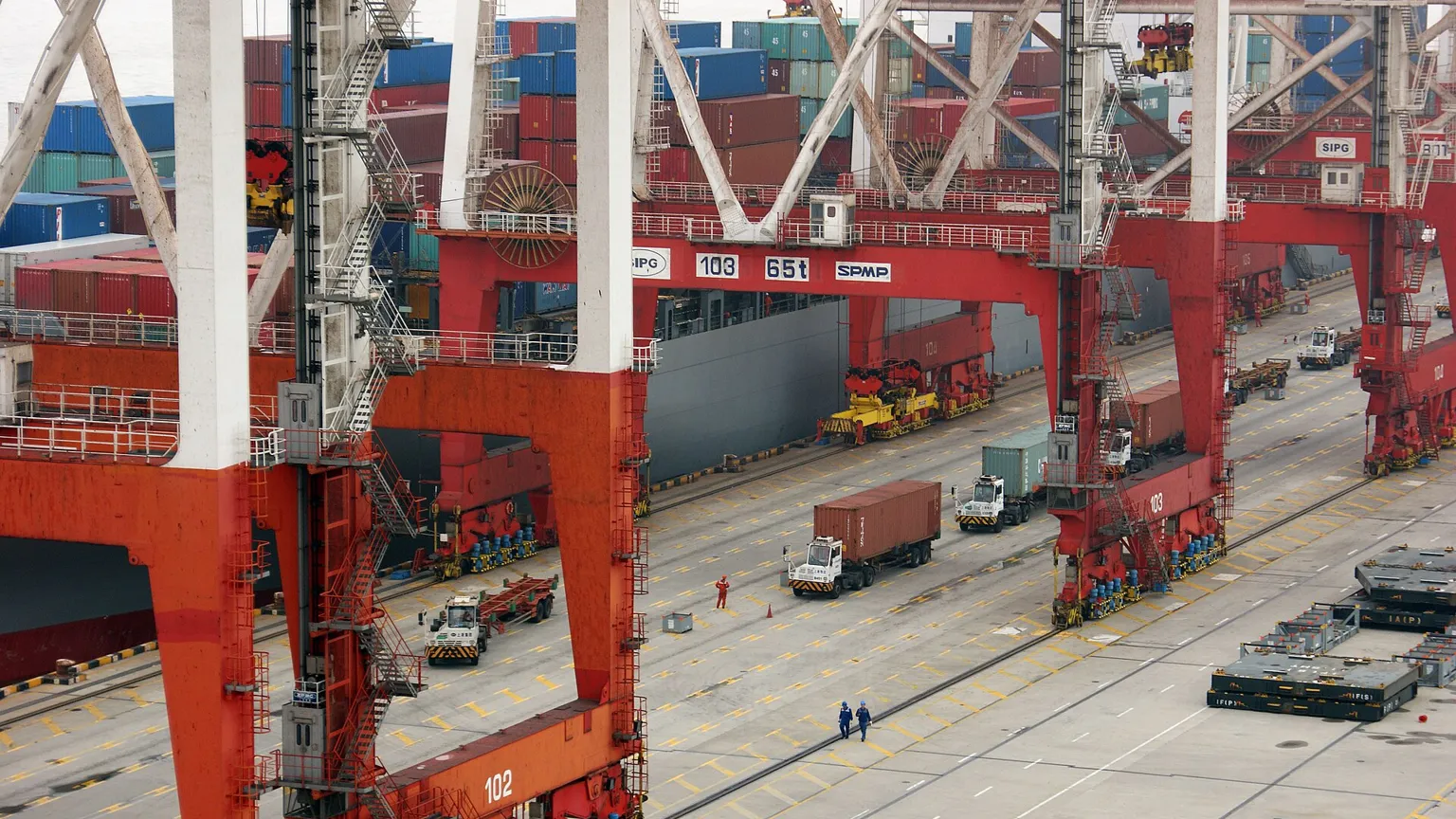 A busy Chinese container port at sunset with cranes loading a cargo ship