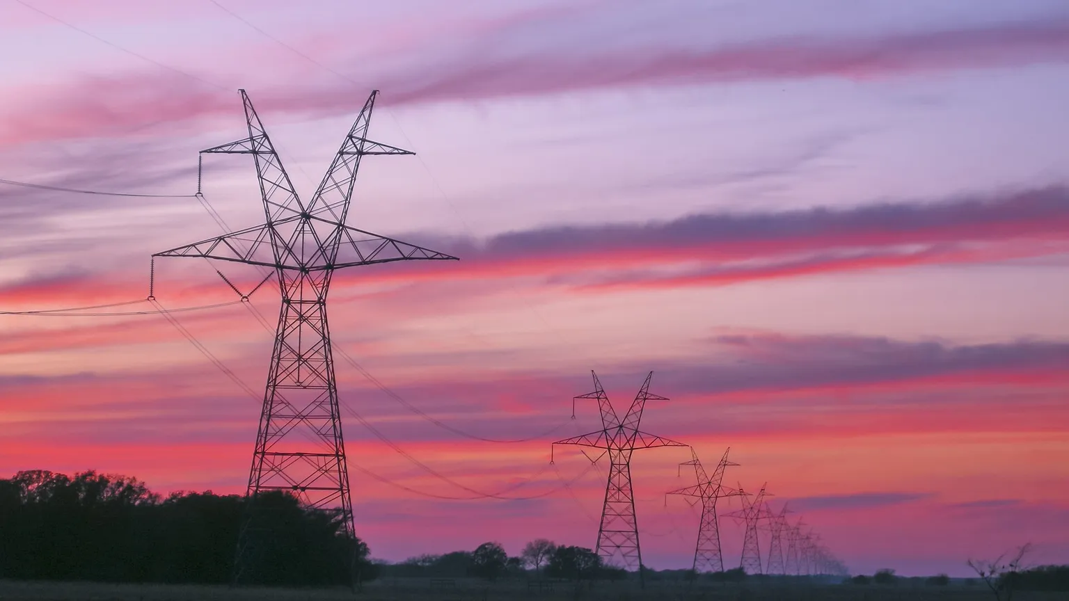 A large windowless data centre on the Texas prairie at dusk with power lines