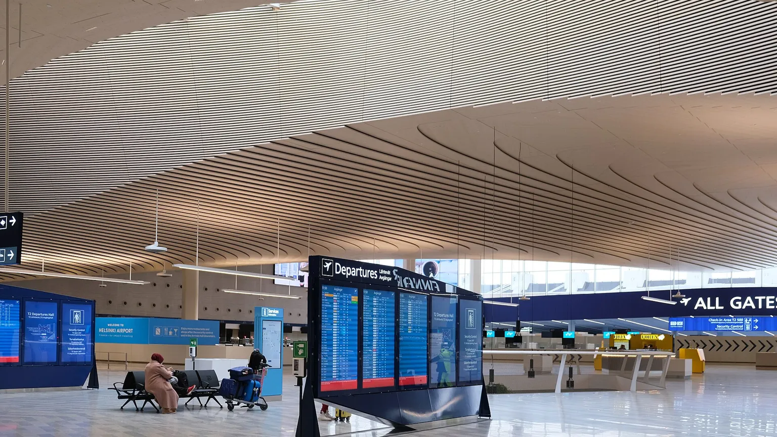 A hand holding a smartphone in a busy airport departure hall